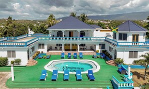 Un complexe hôtelier doté d’une piscine, de nombreuses chaises longues et offrant une vue sur le paysage environnant.