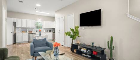 A modern living room with a sofa, coffee table, and a flat-screen TV mounted on the wall.