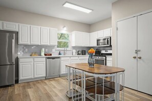 A modern kitchen with white cabinetry, stainless steel appliances, and a wooden island with a vase. - East Austin 4-Bedroom Home, Private Backyard with Plunge Pool & BBQ, Sleeps 11 (Austin)
