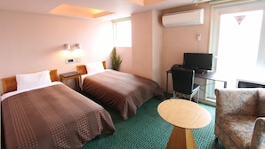 Quarto de hotel com duas camas, televisão, uma mesa pequena e uma cadeira.