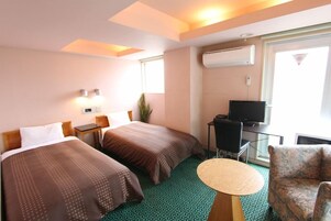 Quarto de hotel com duas camas, televisão, uma mesa pequena e uma cadeira.