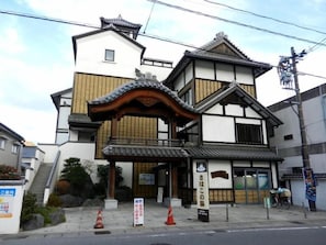 Un edificio tradicional japonés con tejado de tejas, vigas de madera y un letrero.