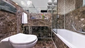 A modern bathroom with a marble sink, a toilet, and a bathtub. - Movenpick MS Hamees (Qena)