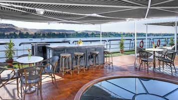 Un espace extérieur abrité comprenant une piscine, un bar et des sièges.