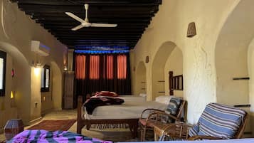 A room with a bed, a chair, a small table, and a ceiling fan.
