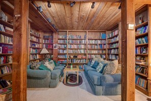 A cozy library with wooden bookshelves, two sofas, and a small table.