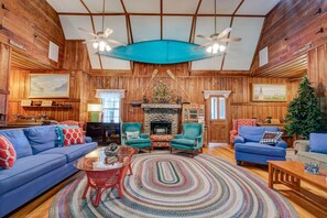 A cozy cabin-style interior with a fireplace, wooden walls, and a large window.