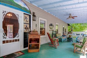 A porch with a covered area, a wooden table with a 'WELCOME' sign, and a 'FAMILY' sign.