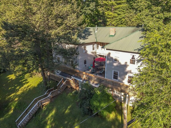 A two-story house with a deck, surrounded by trees.