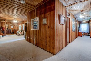 A wooden interior with a central corridor, a bookshelf, and a ceiling fan.