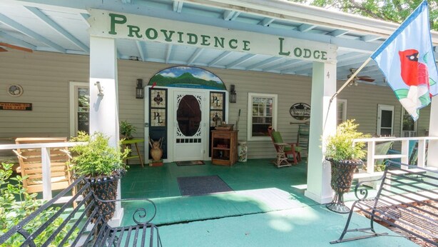 Un edificio con un porche, un letrero que dice 'Providence Lodge' y una bandera con un ave.