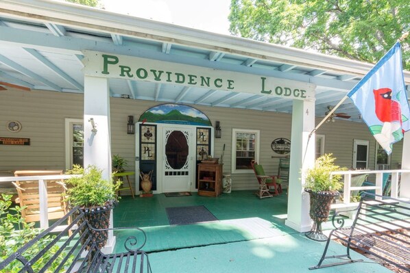 Rakennuksessa on kuisti, ja sen yläpuolella on kyltti, jossa lukee ”Providence Lodge”, sekä lippu, jossa on kuva linnusta.
