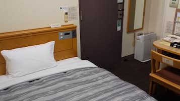 A hotel room with a bed, a desk, a chair, a telephone, and a door.
