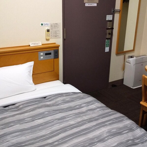Habitación de hotel con cama, panel de control, puerta y espejo.