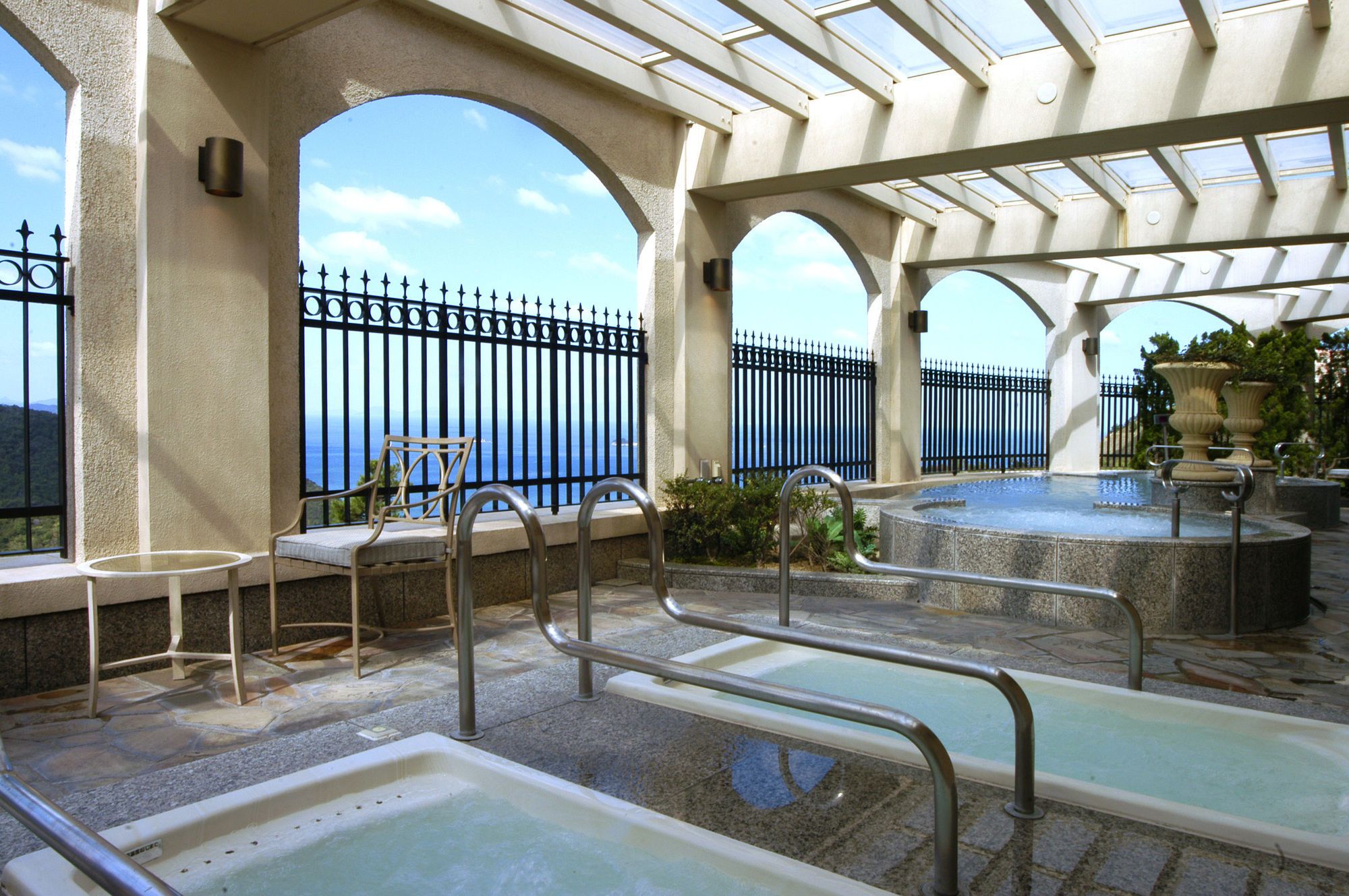 Zona de piscina en la azotea con vista al mar, barandillas metálicas y una silla.
