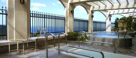 Zona de piscina en la azotea con vista al mar, barandillas metálicas y una silla.