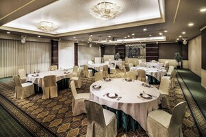 Un salón de conferencias con varias mesas redondas, cada una con sillas y preparación para una comida.