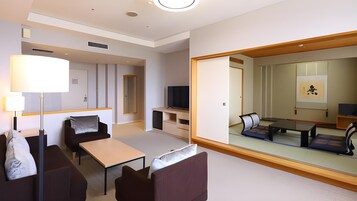 Una habitación de hotel moderna con un sofá, una mesita, un televisor y un espejo grande que refleja la habitación.