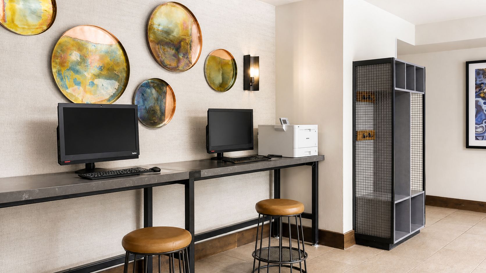 A reception area with two computer monitors, a printer, and a seating area with stools.