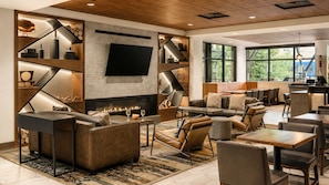 A modern lounge area with a fireplace, seating arrangements, and a large flat-screen TV.