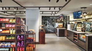 Una tienda moderna con pasillos de aperitivos, un mostrador central y un gran mural en la pared.