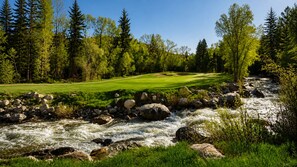 A river flowing through a golf course with a clear path and surrounding greenery.
