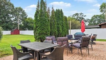 An outdoor patio area with wicker furniture, a table, and chairs.