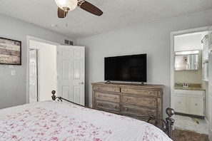 A bedroom with a bed, a dresser, a television, and a door.