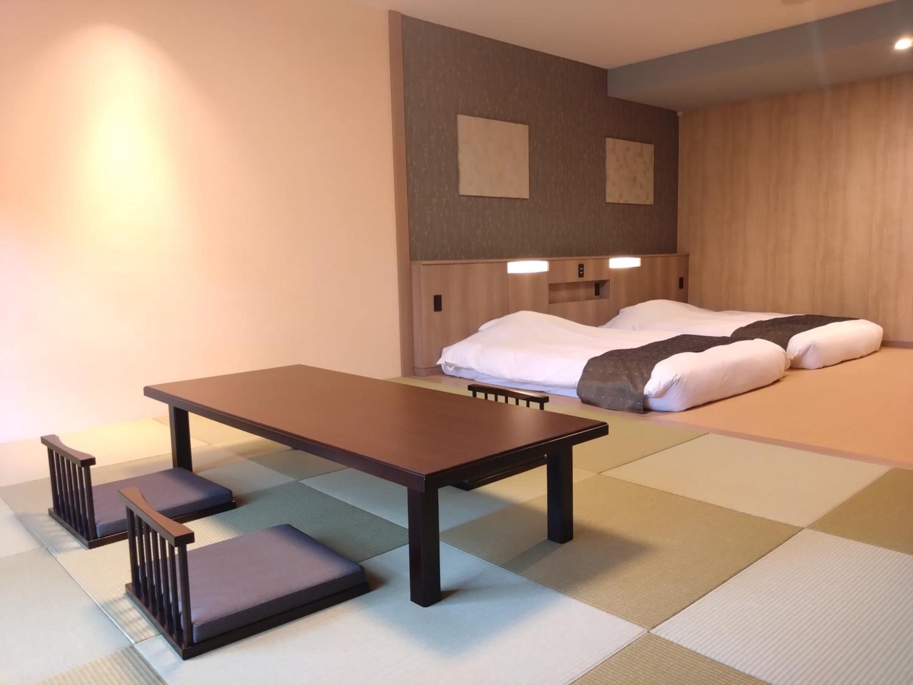 Una stanza con un letto, un tavolo e una panca.