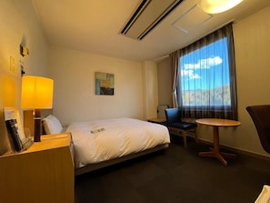 A hotel room with a bed, bedside table, lamp, chair, and a small table. - Hotel Route-inn Chichibu (Chichibu)