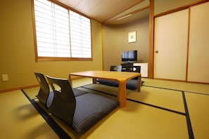 A tatami mat room with a low table and chairs, a television, and sliding doors. - Hotel Route-inn Chichibu (Chichibu)