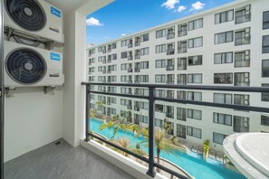 Varanda de hotel com vista para a piscina, unidades de ar condicionado e fachada de edifício moderna.