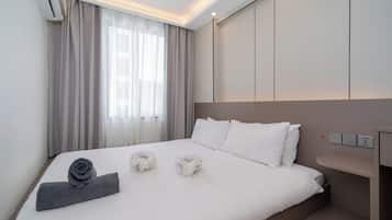 Une chambre d’hôtel avec un lit, une table de chevet, un climatiseur fixé au mur et une fenêtre avec des rideaux.