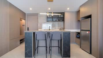 Une cuisine moderne dotée d’un îlot central, de tabourets de bar, d’un réfrigérateur et d’un four encastré.
