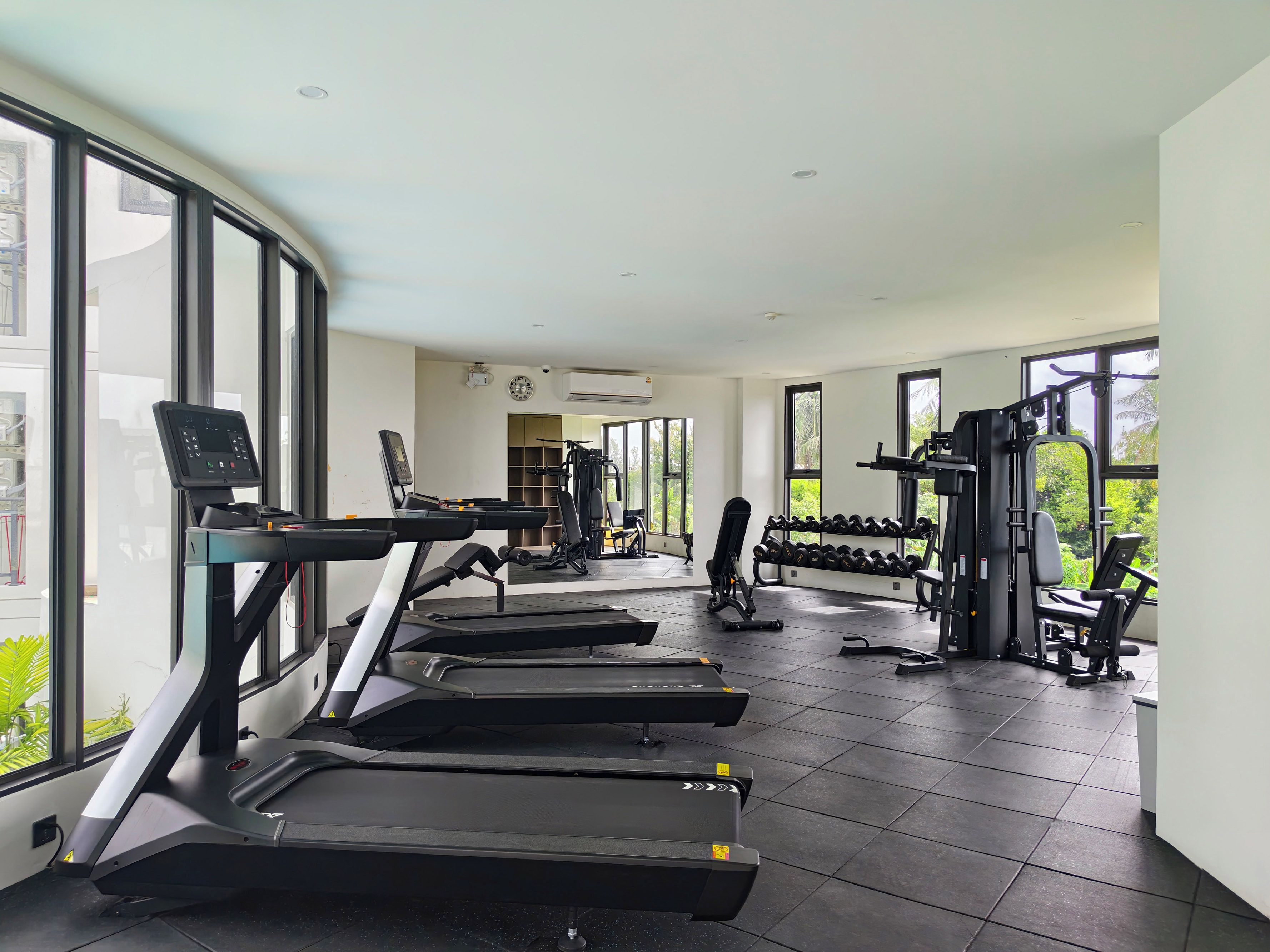 A gym with treadmills, dumbbells, and weight machines.