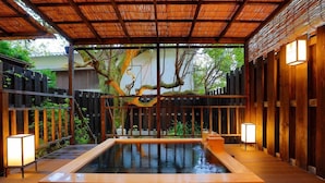 A traditional Japanese onsen with a wooden deck, a glass-enclosed hot spring, and a bamboo roof. - Gyokushoen Arai (Izu)
