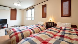 A hotel room with two beds, a television, a small table, and a window.