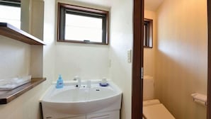 A bathroom with a white sink, a window above it, and a toilet.