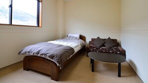 A bedroom with a single bed, a sofa, and a small table.