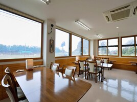 Un salón de conferencias con una mesa grande y sillas, ventanas amplias y un equipo de aire acondicionado.