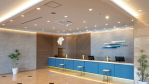 A modern reception area with a blue counter, two bar stools, and a potted plant. - Hotel City Plaza Kitakami (Kitakami)