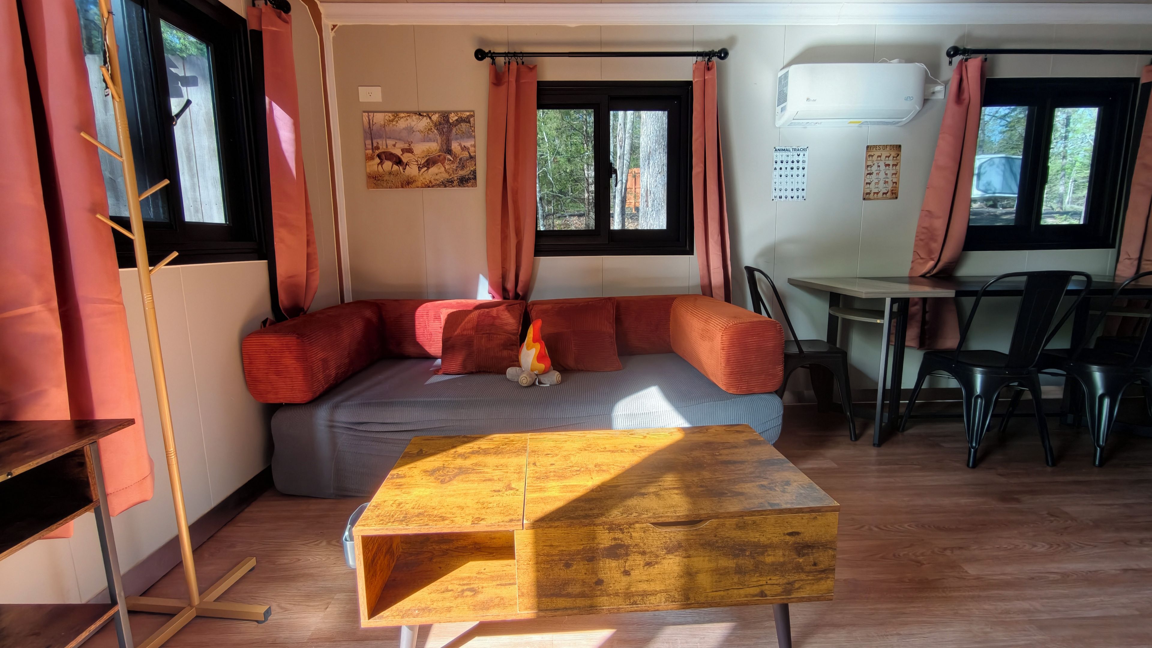 Una habitación acogedora con sofá, mesa y ventana con cortinas.