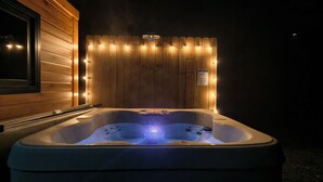Ein Whirlpool mit einer Holzverkleidung und Lichterkette im Hintergrund.