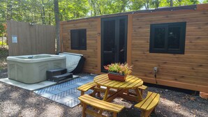 Eine Holzhütte mit Whirlpool, überdachter Veranda und Picknicktisch.