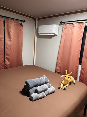 Ein Zimmer mit einem Bett, einer Wandklimaanlage und einem Kuscheltier auf dem Bett.