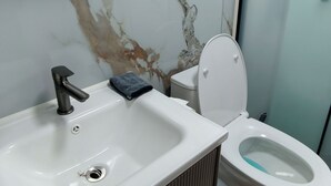 Ein Badezimmer mit einem weißen Waschbecken, einer Toilette und einer Marmor-Spritzschutzwand.