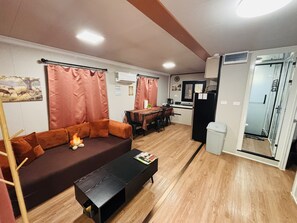 A living room with a sofa, coffee table, and a dining area with a table and chairs.