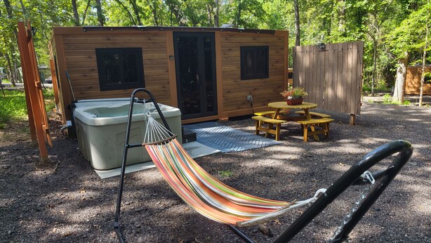 Eine Holzhütte mit Whirlpool, Hängematte und Picknicktisch.