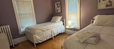 Un dormitorio con dos camas, suelo de madera y un radiador.