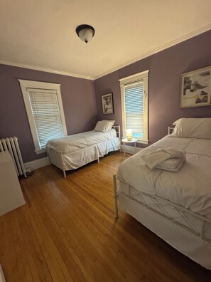 Ein Schlafzimmer mit zwei Betten, Holzboden und einem Heizkörper.
